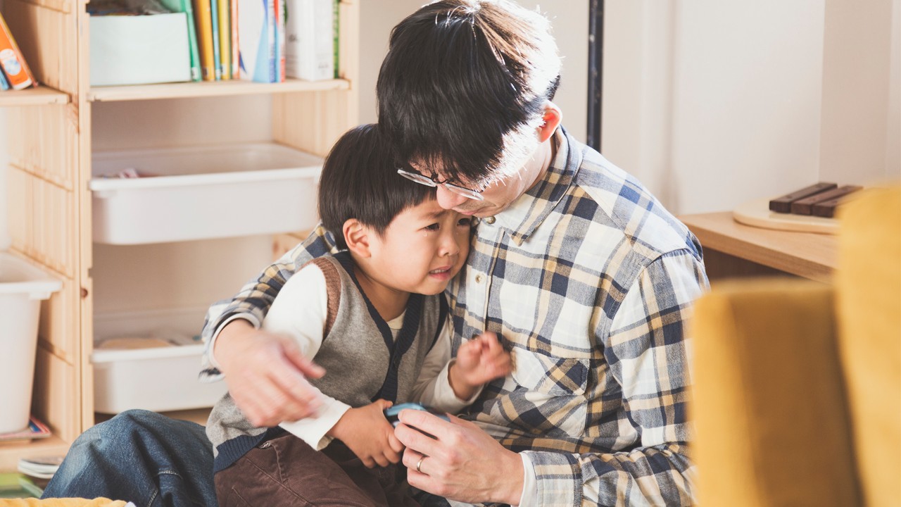 A father embracing crying son.