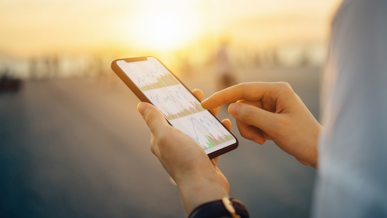 Close-up shot of hands interacting with smartphone with charts on screen; image used for HSBC Fund Prices