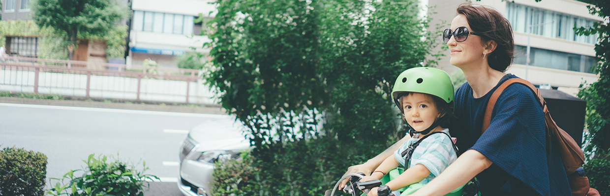 Woman in sunglasses rides bicycle with child in a helmet; image used for HSBC Protection